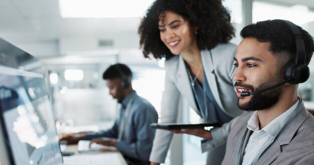 A man in a headset next to a girl looking at the monitor